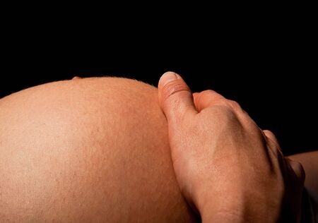 Closeup of a hand and a pregnant bellyの写真素材