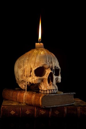 Halloween image with a burning candle on an ancient skullの写真素材