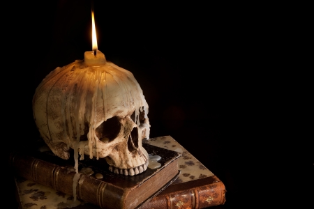 Halloween image with a burning candle on an ancient skullの写真素材
