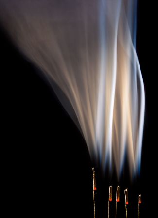 Incense burning with beautiful smoke fumes and wispsの写真素材