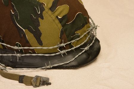 Helmet with barbed wire lying in the sandの写真素材
