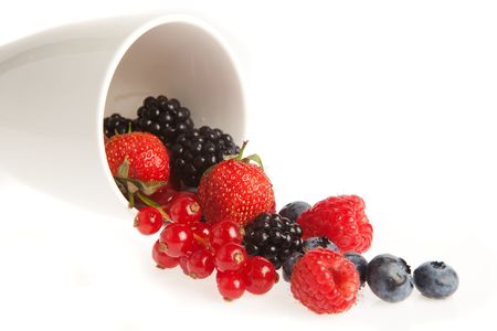 Delicious summer fruits and berries rolling out of a white mugの写真素材