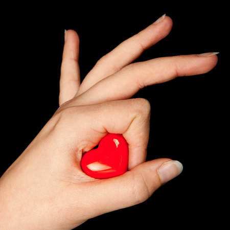 Female hand holding a little red valentine heart