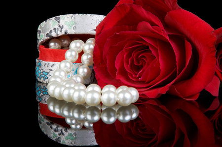 Little box filled with a pearl necklace and a perfect red roseの写真素材