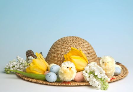 Straw hat decorated for easter with flowers, chicks and easter eggsの写真素材