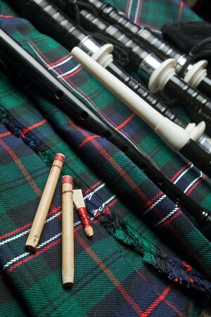 Authentic bagpipe reeds and bagpipes lying on a scottish tartan kiltの写真素材