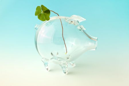Four-leafed clover in an empty glass piggybankの写真素材