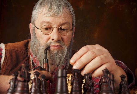 Vintage scene of an old man thinking about his next move in a chess gameの写真素材