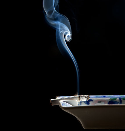 Cigarette on ashtray with a beautiful wisp of smokeの写真素材