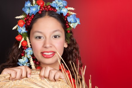 Summer woman with strawberries, fruit and flowers in her hair holding a straw hatの写真素材