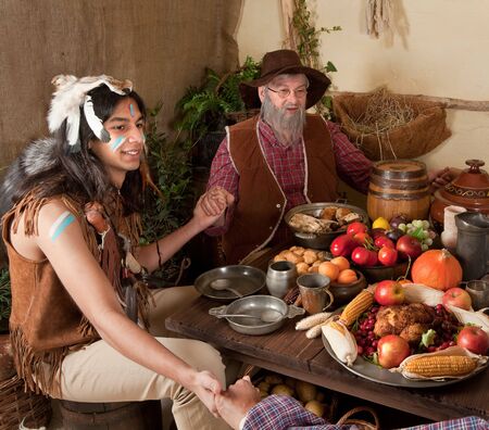 Reenactment scene of the first Thanksgiving Dinner in Plymouth in 1621 with a Pilgrim family and a Wampanoag Indianの写真素材