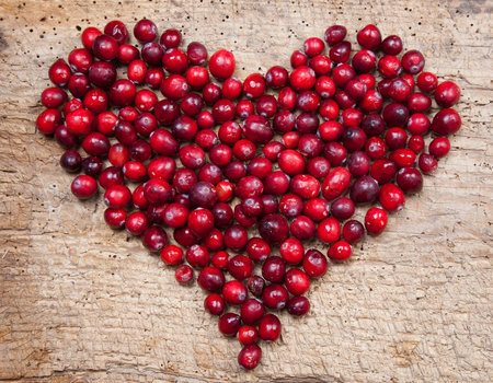 Heart of fresh cranberries on a wooden boardの写真素材