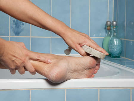 Hand removing callus from feet using pumice stoneの写真素材