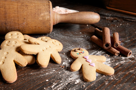 Rolling pin and homemade gingerbread men biscuits on a wooden board with flour