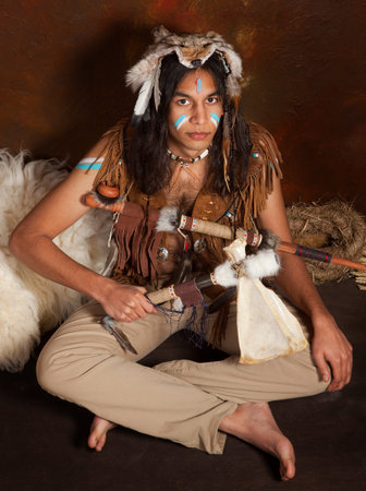 Portrait of an Indian in traditional costume wearing eagle feathers, coyote fur and beads