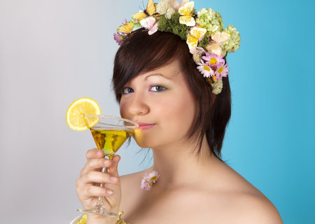 Springtime woman with butterfly and flower hair drinking a cocktailの写真素材