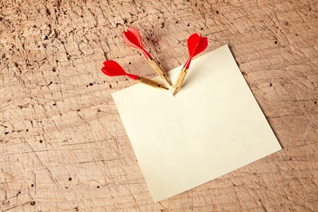Three darts in an empty or blank notepad on a vintage wooden boardの写真素材