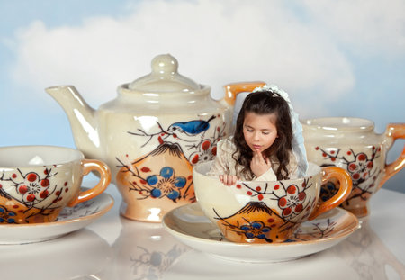 Tea party with antique tea cups and a miniature girl like in alice in wonderlandのeditorial素材