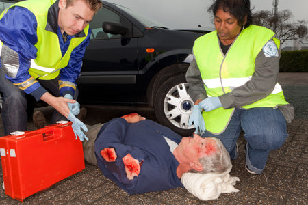 Paramedics putting on sterile gloves to care for a car crash victim  (the sleeve badges have been...