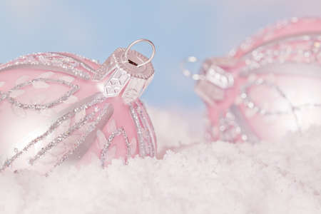 Pair of soft pink christmas decoration lying in the snowの写真素材