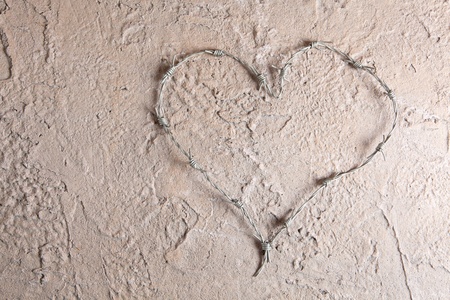 Barbed wire bent into a heart shape on a grunge backgroundの写真素材