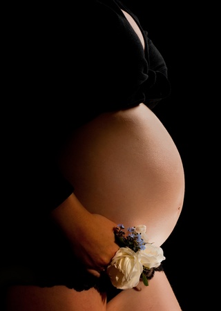 Pregnant woman holding white roses against her bellyの写真素材