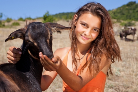 Young cattle girl feeding goats in the Bulgarian mountainsの写真素材