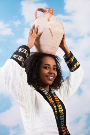 Young African Ethiopian woman carrying a jug or stone pitcherの写真素材