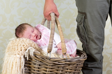 Hands of a father carrying a wicker shopping basket with his 11 days old newborn baby girlの写真素材