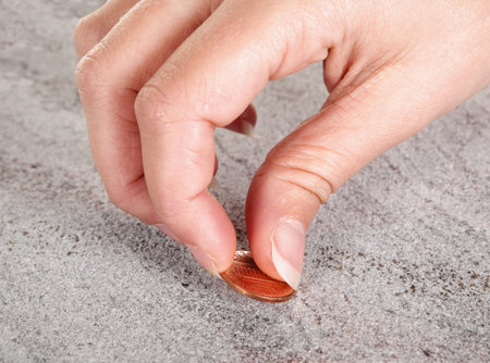 Female hand finding a copper cent or money on a pavement