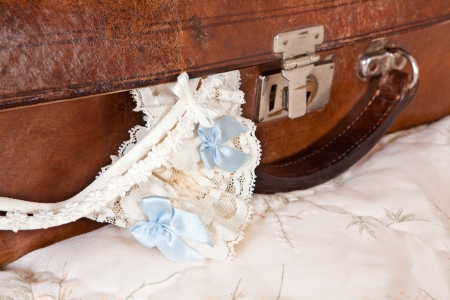 Wedding garter and bra straps hanging out of a vintage suitcaseの写真素材