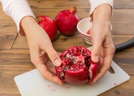 Hands opening a pomegranate and showing the seedsの写真素材