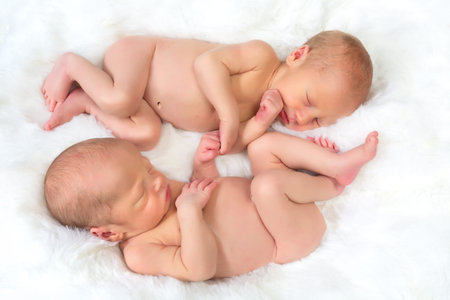 Newborn baby twins sleeping in Ying Yang position, holding hands