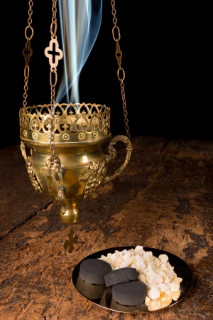 Smoking incense thurible and a golden plate with franincense and charcoal piecesの写真素材