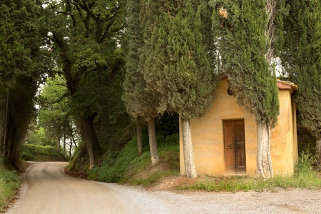 Little forest chapel and winding road in the hills of Tuscany near Pienzaの写真素材