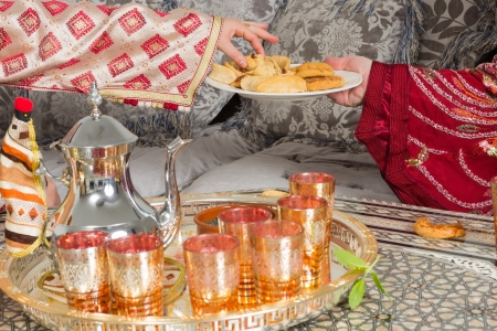 Traditional Moroccan immigrant women presenting typical Ramadan cookies and teaの写真素材