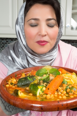 Moroccan immigrant woman in Europe presenting her tajine dish during Ramadan in her modern kitchenの写真素材