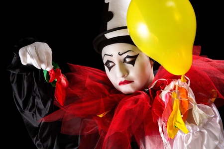 Sad Pierrot clown holding the left-overs of his balloonsの写真素材