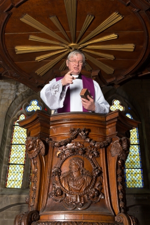 Mature priest preaching in a beautiful antique 17th century wooden pulpitの写真素材