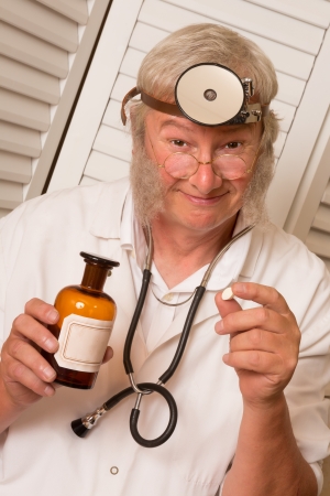 Vintage doctor telling the patient to open his mouth for a big pillの写真素材