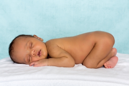 11 days old sleeping african baby on a white towelの写真素材