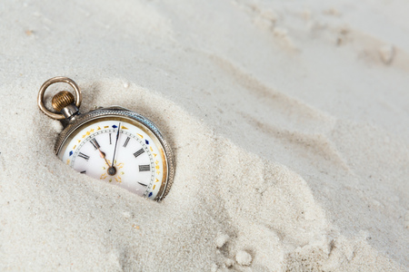 Old beautiful pocket watch lying in the beach sandの写真素材
