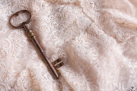 Rusty old key lying on fine antique white laceの写真素材