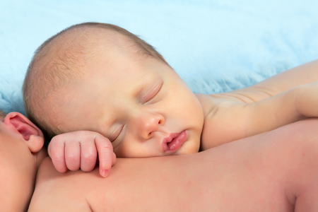 Two adorable newborn twin babies asleep on a soft blanketの写真素材