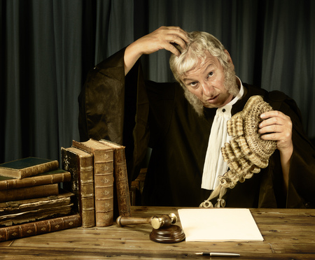 Old judge scratching his head in courtの写真素材