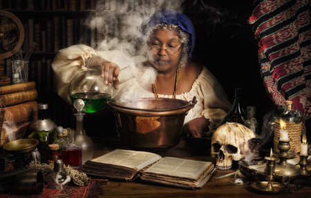 Female alchemist preparing green liquids in a smoking kettleの写真素材