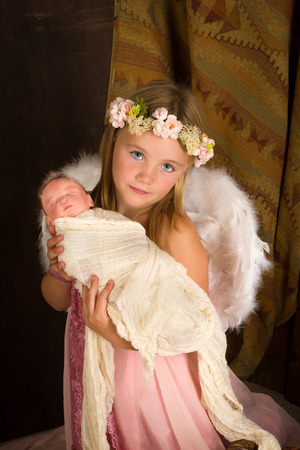 Pink little girl playing an angel in a Christmas nativity scene with a dollの写真素材