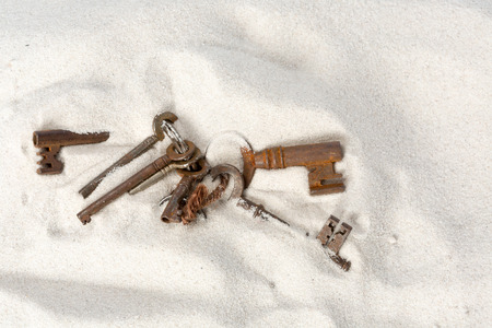 Rusty keys lost in the sand on the beachの写真素材