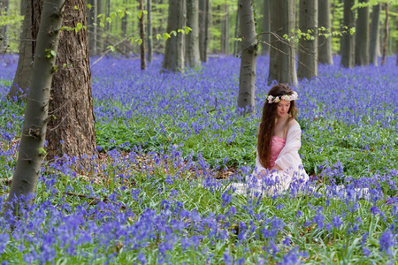 Innocent young woman with pink fairy dress in a springtime bluebells forestの写真素材