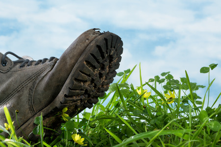 Large boot stepping in grass in extreme closeup symbol for ecological footprintの写真素材